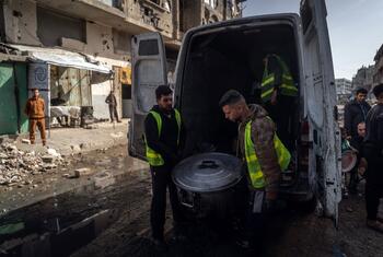تطرد المتطوعون وعاءً كبيرًا من الطعام من شاحنة في غزة، حيث يقدمون وجبات ساخنة للعائلات النازحة خلال شهر رمضان وسط الأنقاض والدمار.