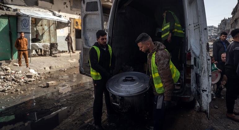 متطوعان ينزلان قدرا كبيرا من الطعام من شاحنة صغيرة في غزة.
