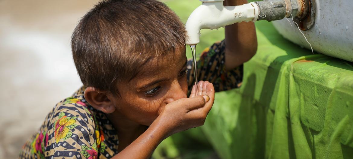 Un niño de 5 años bebe agua de un punto de agua instalado por UNICEF en un campamento provisional del distrito de Larkana, provincia de Sindh, Pakistán.