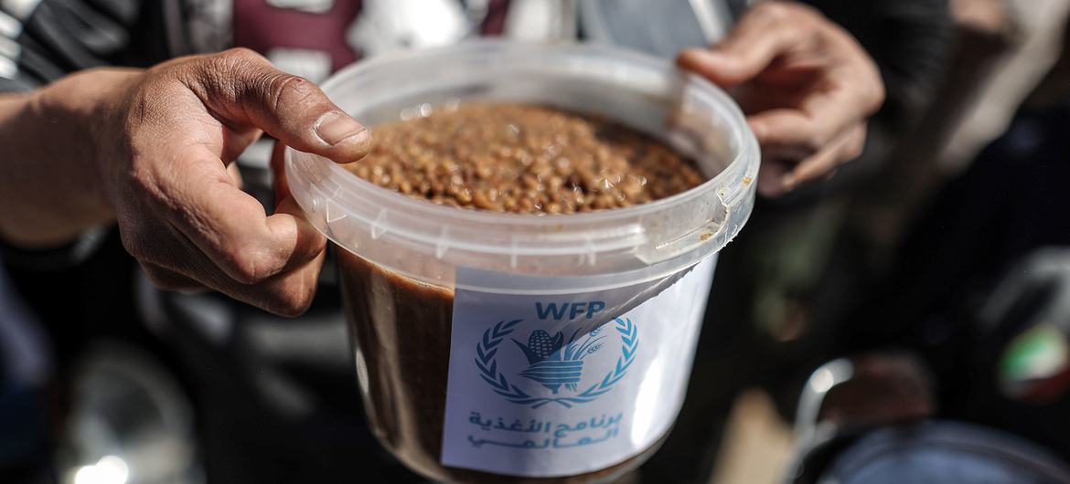 Morador de Gaza segura uma refeição quente distribuída pelo Programa Mundial de Alimentos da ONU.