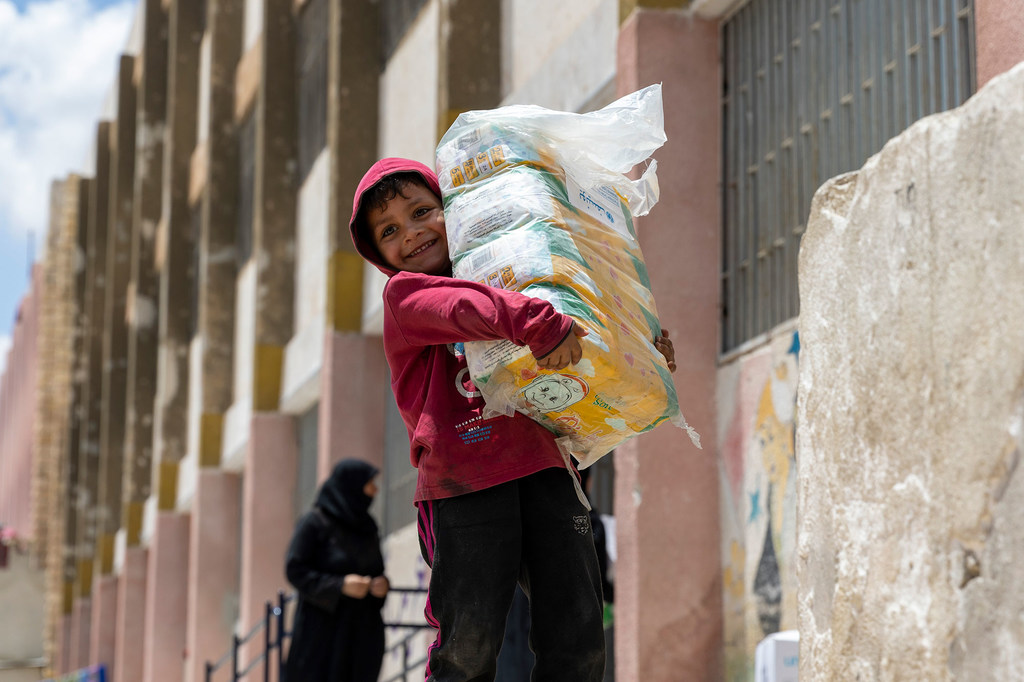 Un garçon de cinq ans collecte des fournitures ménagères distribuées par l'UNICEF dans la ville d'Alep, en Syrie.