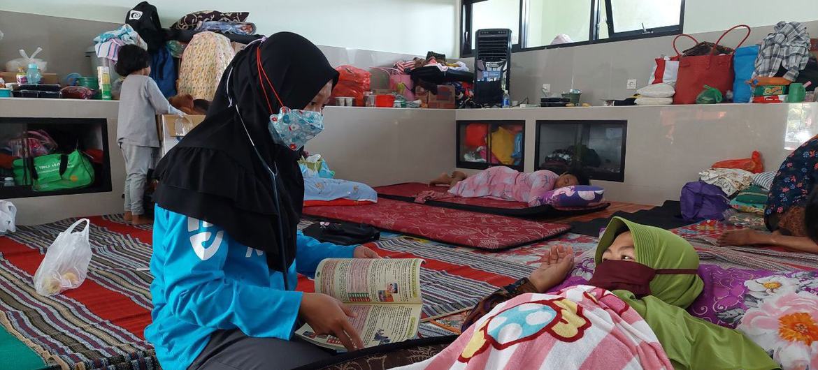 Bidan Indonesia Restu Nur Intan Pratiwi, 25, merawat seorang penyintas di pusat evakuasi setelah letusan Gunung Semeru di Jawa Timur, Indonesia pada Desember 2021.