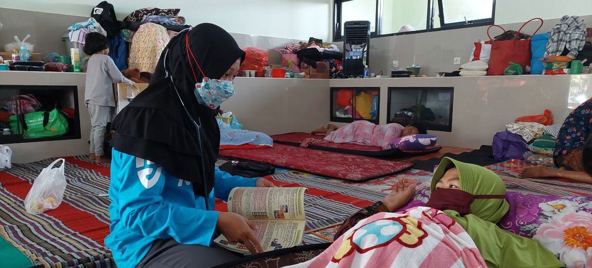 Indonesian midwife Restu Nur Intan Pratiwi, 25, attends to a survivor at an evacuation center after the Mount Semeru eruption in  East Java, Indonesia in December 2021.