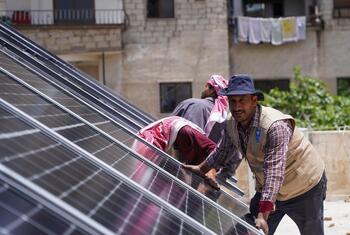 A UNDP project team installs solar panels on a rooftop at a Health Center in Jaramana, Rural Damascus, Syria, with support from KFW8.