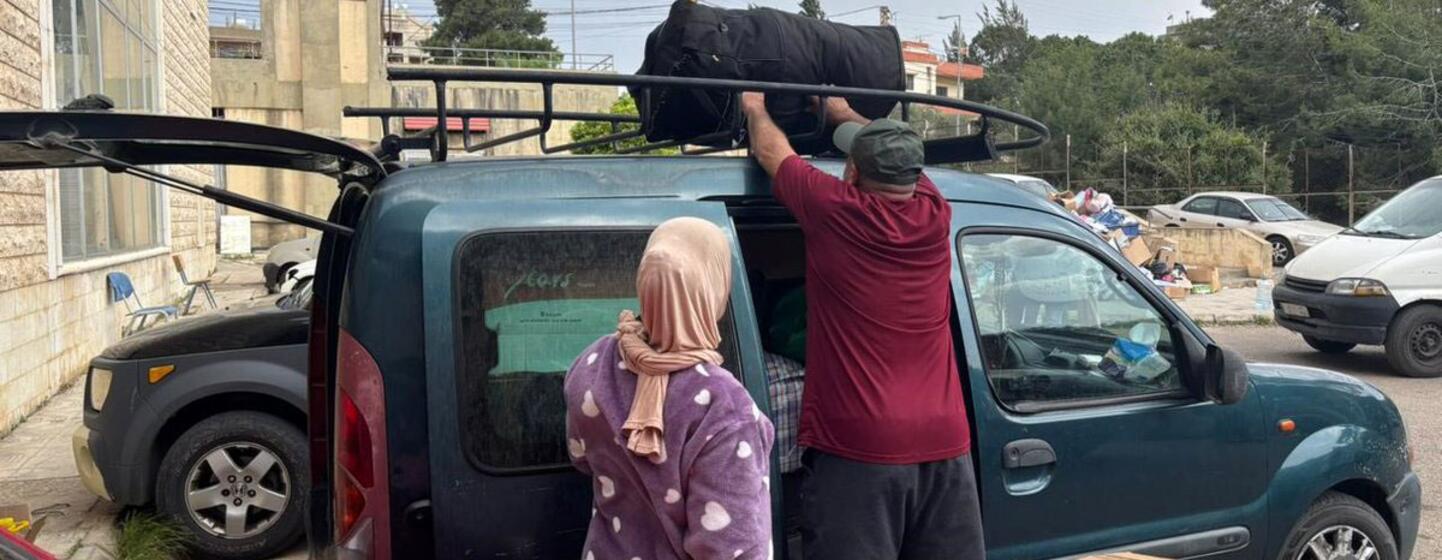 Un membre de l'équipe de l'OMS aide une famille déplacée à charger ses affaires sur un porte-bagages de toit dans un abri à Chhim, au Liban, alors qu'elle se prépare à rentrer chez elle après un cessez-le-feu.