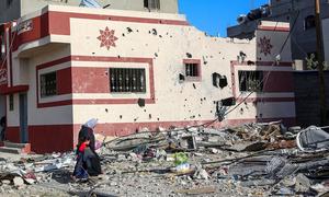 A woman and child walk through the heavily bombed town of Khuza'a in the Gaza Strip.