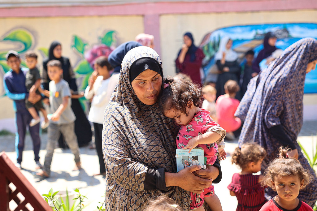 Una mujer sostiene a su hija mientras esperan durante una revisión nutricional en una clínica apoyada por UNICEF en la Franja de Gaza.