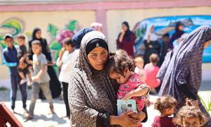 Una mujer sostiene a su hija mientras esperan durante una revisión nutricional en una clínica apoyada por UNICEF en la Franja de Gaza.