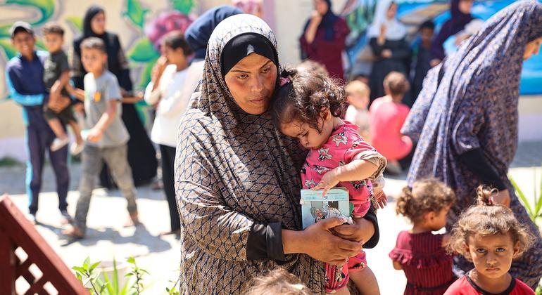 Una mujer sostiene a su hija mientras esperan durante una revisión nutricional en una clínica apoyada por UNICEF en la Franja de Gaza.