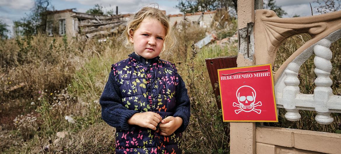 Veronika, 4 ans, se tient près d'un panneau indiquant "Danger de mines", à Chistovodivka, dans la région de Kharkiv, en Ukraine.