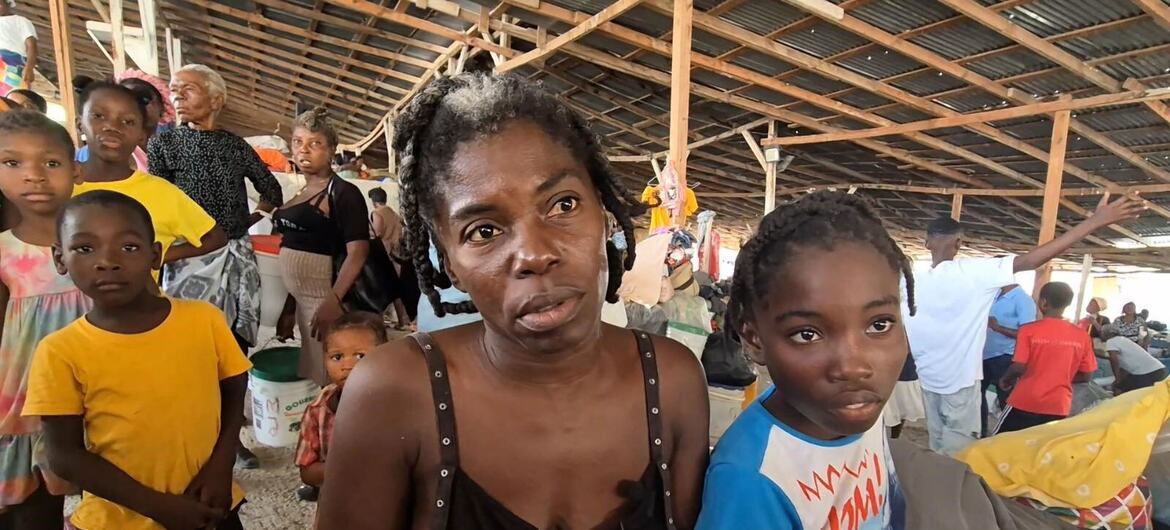 Haitian refugees, including a woman and two children, look at the camera inside a shelter in Drouillard, Port-au-Prince.