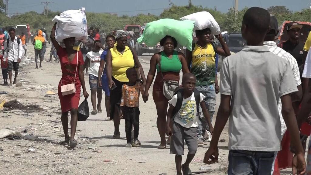 People who have fled their homes carry possessions through the streets of Port-au-Prince.