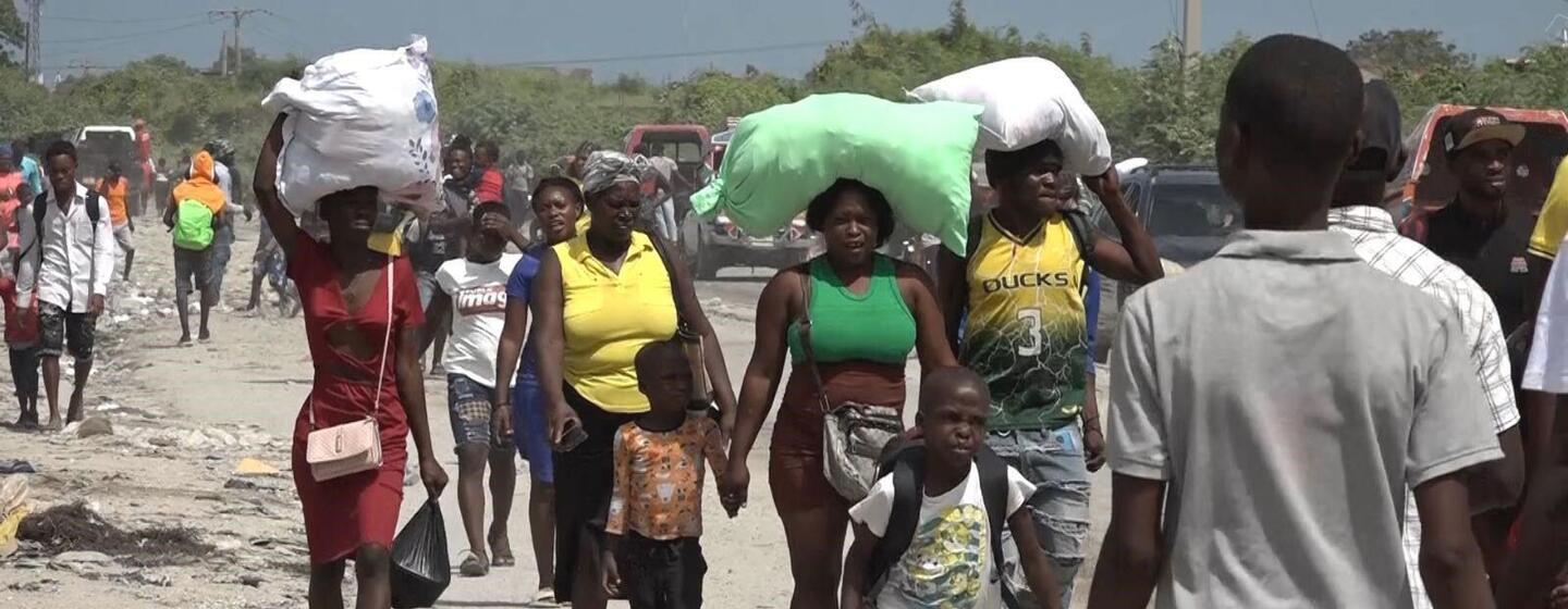 Des réfugiés, dont des familles avec enfants et des personnes âgées, fuient par une route de terre à Drouillard, près de Port-au-Prince, en Haïti, après des affrontements entre groupes armés.