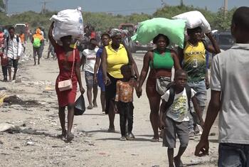 Refugees, including families with children and elderly people, flee through a dirt road in Drouillard near Port-au-Prince, Haiti, after clashes between armed groups.