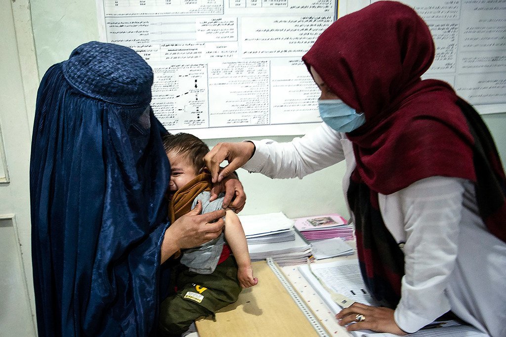 2020年11月，阿富汗帕尔万省，一名卫生工作者在照顾一名小男孩。