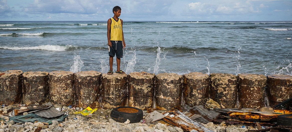 Un niño en el dique que protege el hogar familiar de las mareas crecientes del atolón de Majuro en las Islas Marshall.