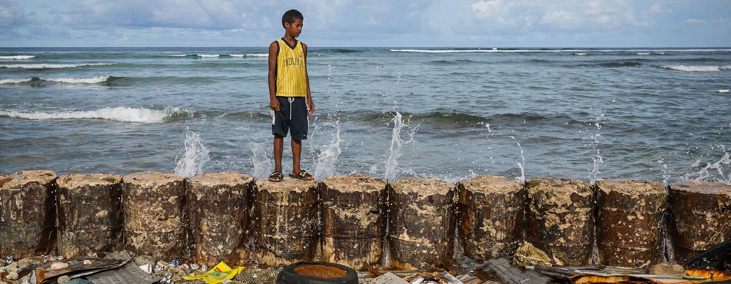 A boy stands on a seawall that protects his family home from the rising seas in Majuro Atoll in the Marshall Islands.