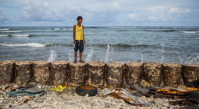 Un niño en el malecón que protege el hogar familiar de las mareas crecientes del atolón de Majuro en las Islas Marshall.