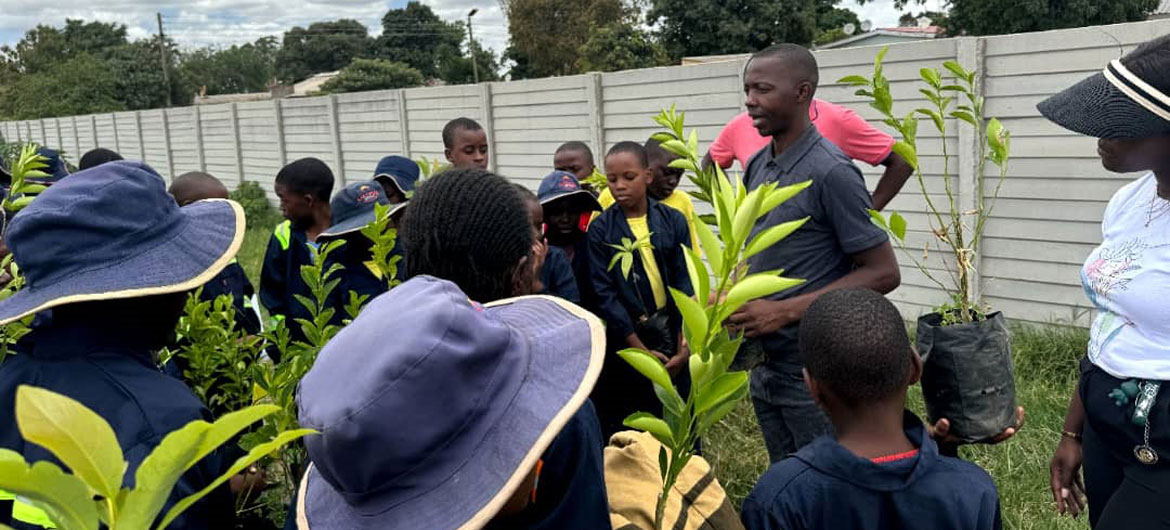 Takudzwa Ashley Mlambo (right) talks to young people in a garden in Zimbabwe.