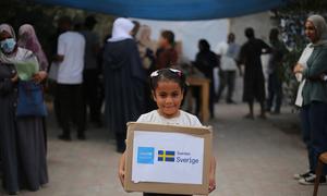 A child in Gaza carries a box of winter clothes.