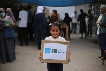 A child in Gaza carries a box of winter clothes.