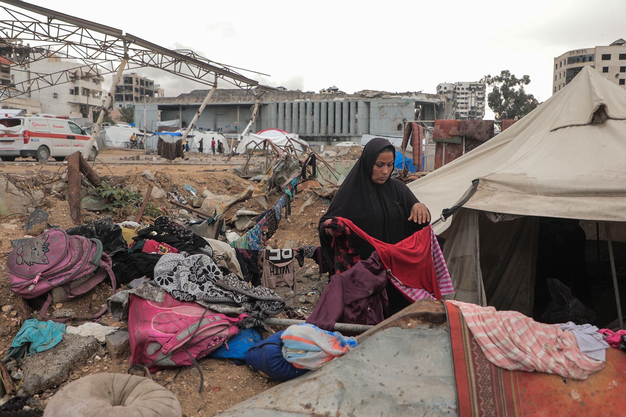 Une femme trie des vêtements devant sa tente à Gaza.