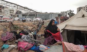 A woman sorts through clothes outside a tent in Gaza City.