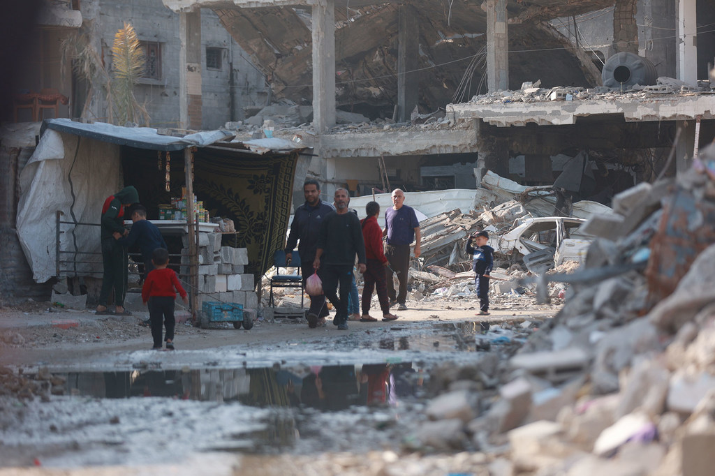 人们走过加沙城一片沦为废墟的街区。