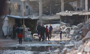 People walk through a destroyed neighbourhood of Gaza City.