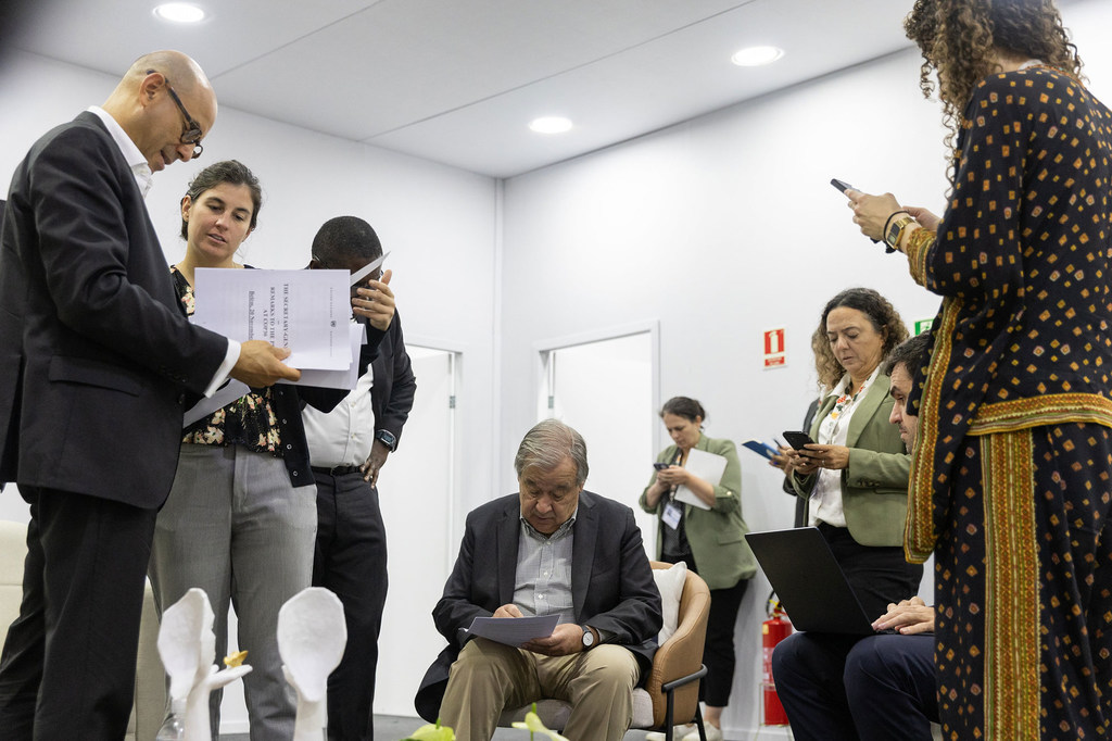 Le Secrétaire général de l'ONU, António Guterres (au centre), examine des documents avec ses collègues lors de la Conférence des Nations Unies sur le climat au Brésil.