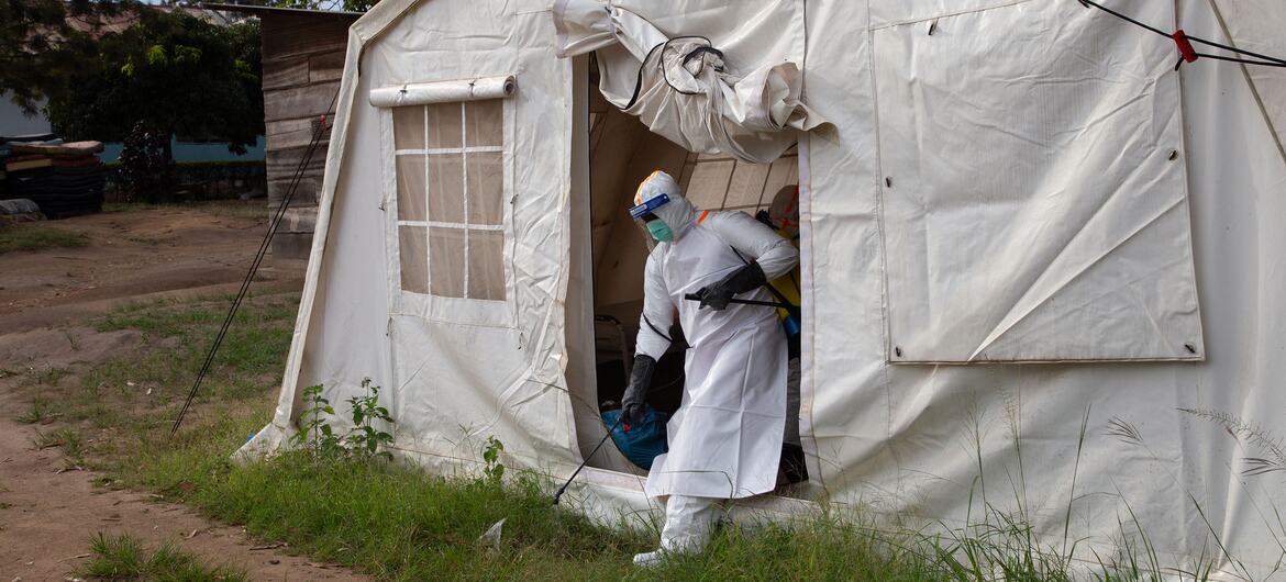 Un trabajador sanitario con equipo de protección completo desinfecta un hospital de campaña con la marca UNICEF en Bunia, República Democrática del Congo.