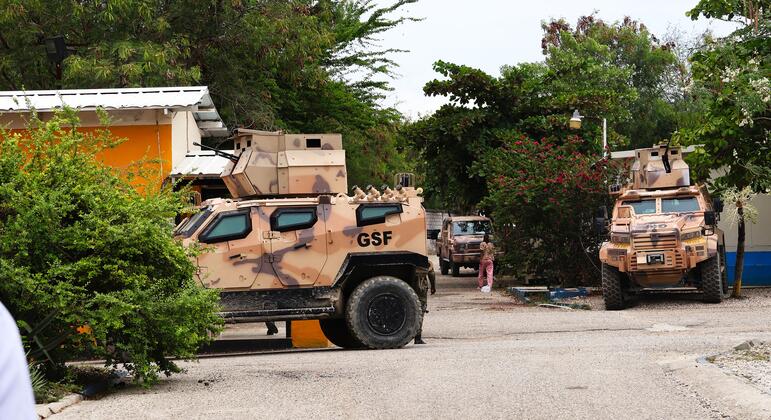 Armored military vehicles with GSF markings are parked on a gravel road at a military base in Haiti.