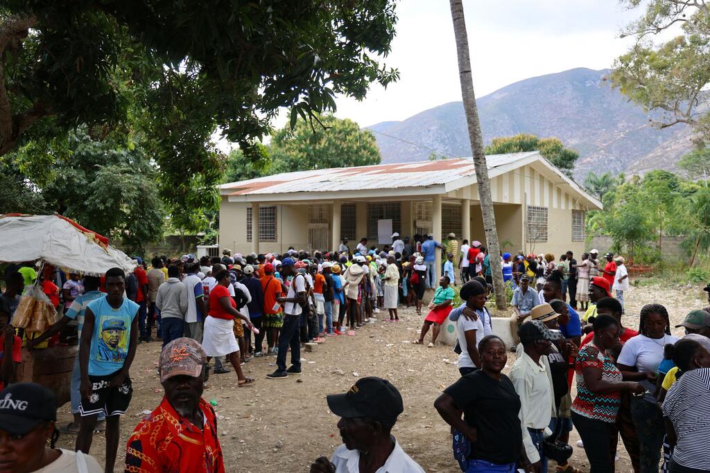 Des participants font la queue devant un bâtiment pour une distribution de travail contre rémunération du Programme alimentaire mondial en Haïti.