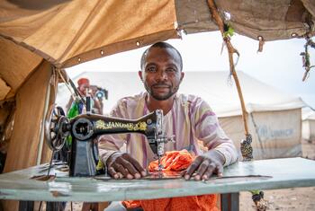 Muhigirwa Balyahamwabo, a refugee tailor from the Democratic Republic of the Congo, operates a sewing machine at his shelter in the Kakuma refugee camp in Kenya.
