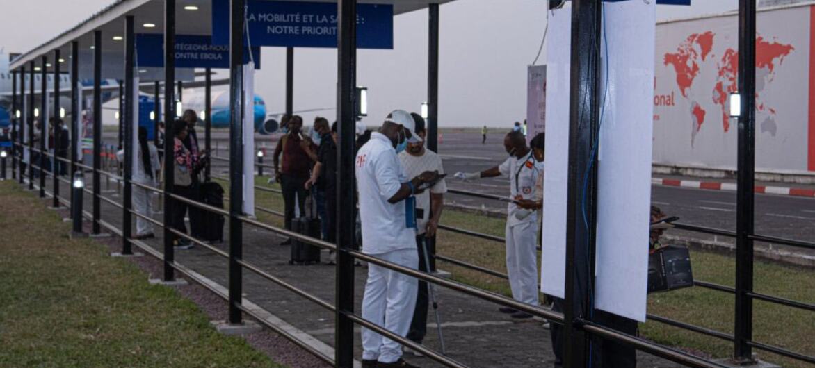 Personal sanitario con uniformes blancos y mascarillas examina a los viajeros en una terminal de aeropuerto en la República Democrática del Congo durante el brote de ébola.