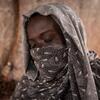 Суданская женщина в узорчатом платке сидит в палатке в лагере для перемещенных лиц в Северном Дарфуре.