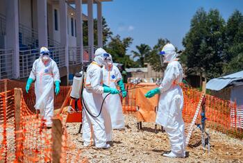 Health workers in full protective gear disinfect a site with a sprayer during a WHO response to an Ebola outbreak in the Democratic Republic of the Congo.
