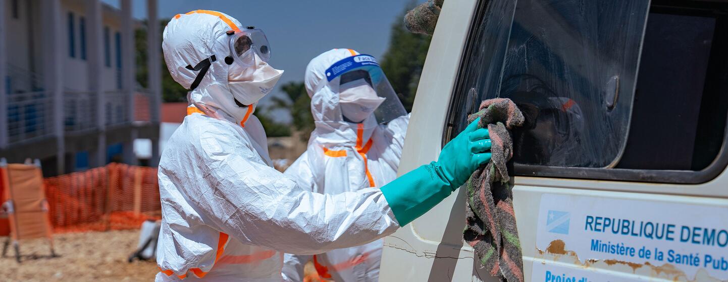 Des agents de santé de l'OMS, vêtus d'équipements de protection, nettoient un véhicule lors d'une opération de lutte contre Ebola en République démocratique du Congo.