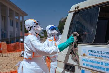 WHO healthcare workers in protective gear clean a vehicle during an Ebola response operation in the Democratic Republic of the Congo.