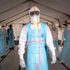 Des agents de santé entièrement équipés de protections individuelles (EPI) se tiennent à l'intérieur d'une tente médicale lors d'une intervention contre une épidémie d'Ebola en Ouganda.