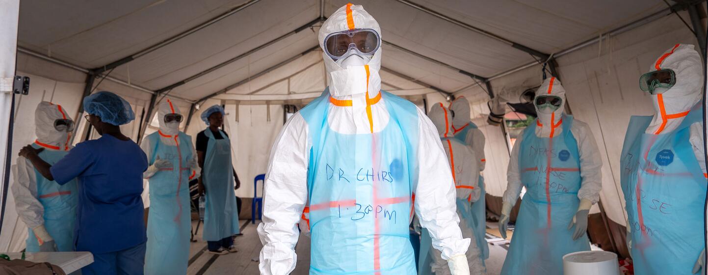 Des agents de santé entièrement équipés de protections individuelles (EPI) se tiennent à l'intérieur d'une tente médicale lors d'une intervention contre une épidémie d'Ebola en Ouganda.