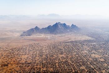 Vue aérienne d'une grande agglomération dans un paysage désertique avec des montagnes en arrière-plan, identifiée comme Kassala, au Soudan.