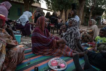 Displaced women and children from Khartoum sit on a mat outside an IDP site in Kassala, Sudan, in 2026.