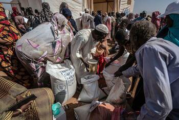 People at a World Food Program food distribution site in Gharb Al Matta, Kassala, Sudan, receiving bags of sorghum, lentils, and cooking oil.