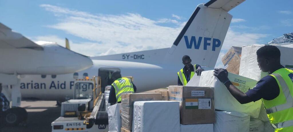 À l'aéroport international d'Entebbe, des employés du PAM, vêtus de gilets de sécurité, déchargent des fournitures de secours d'urgence, notamment des biscuits énergétiques et des EPI, d'un avion affrété par le PAM lors de la riposte contre Ebola en RDC.