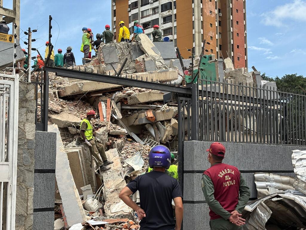 Los equipos de rescate buscan entre los escombros de un edificio derrumbado en un suburbio de Caracas tras el terremoto en Venezuela.