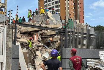 Des secouristes équipés de tenues de sécurité évaluent les décombres d'un immeuble effondré au Venezuela à la suite d'un tremblement de terre.