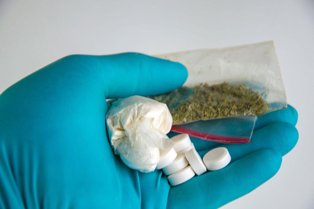 一名实验室工作人员手持合成毒品和大麻的样品。