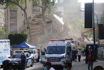 Véhicules et personnel d'intervention d'urgence sur le site d'un immeuble effondré au Venezuela suite à un tremblement de terre.