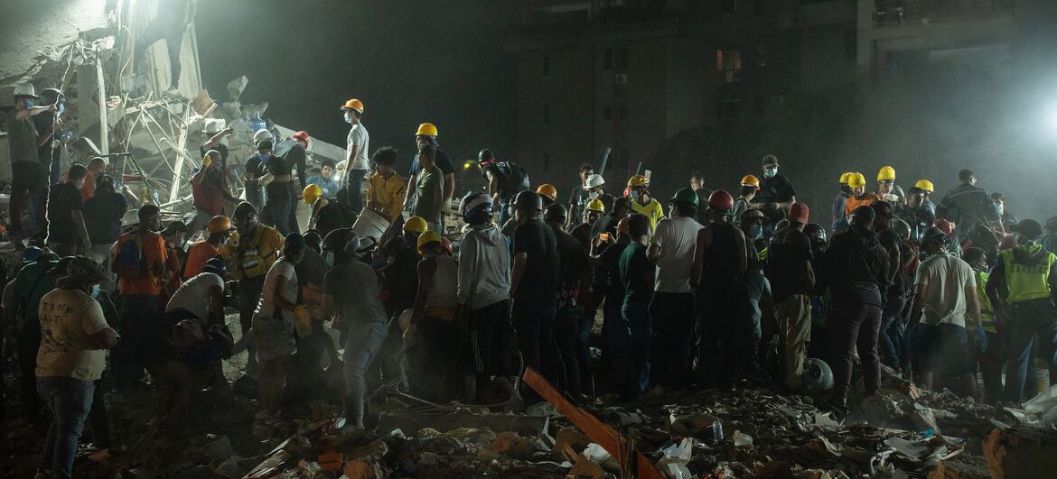 地震后，委内瑞拉一处建筑工地倒塌，救援人员头戴黄色安全帽在废墟中搜寻。